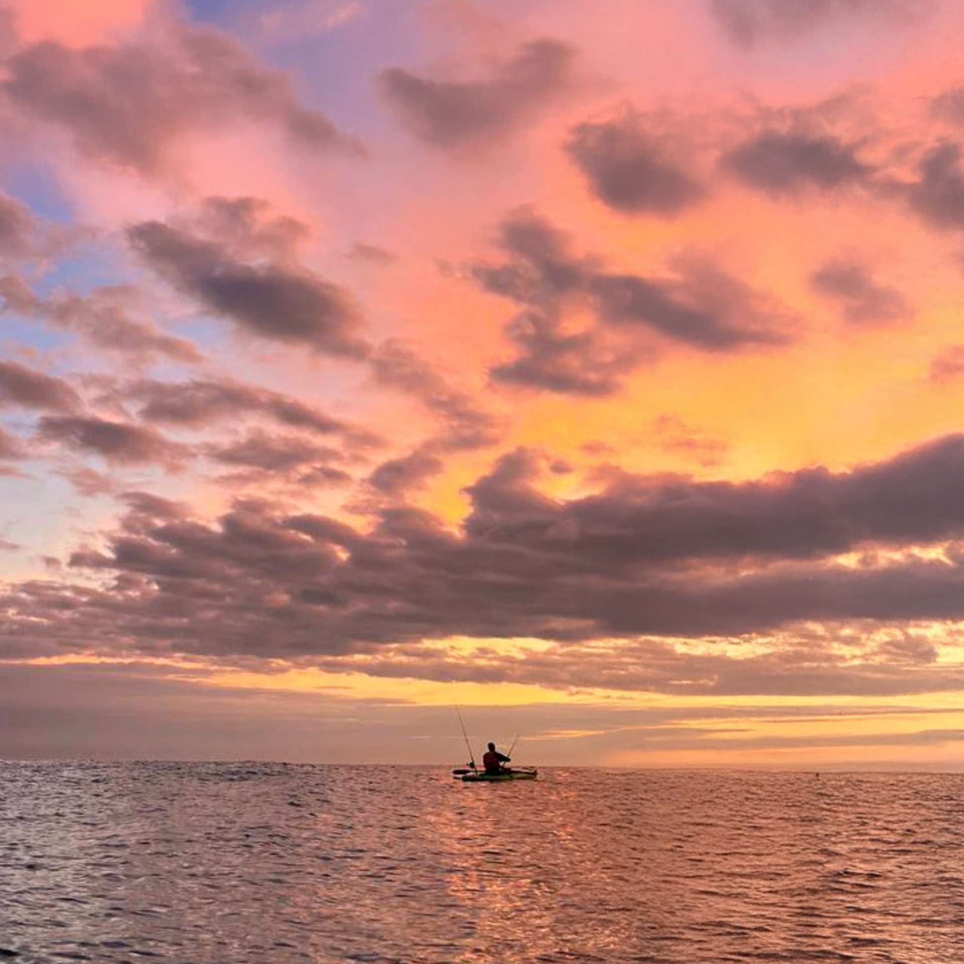 Kayak fisherman on the water under a sunrise sky