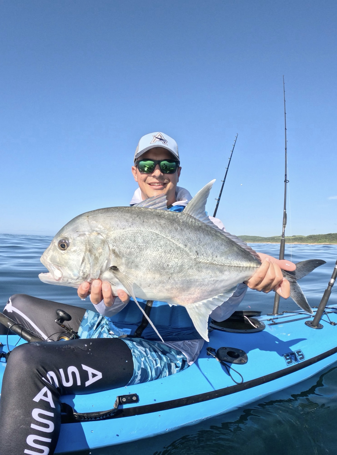 Kayak angler holding up a big catch on the water