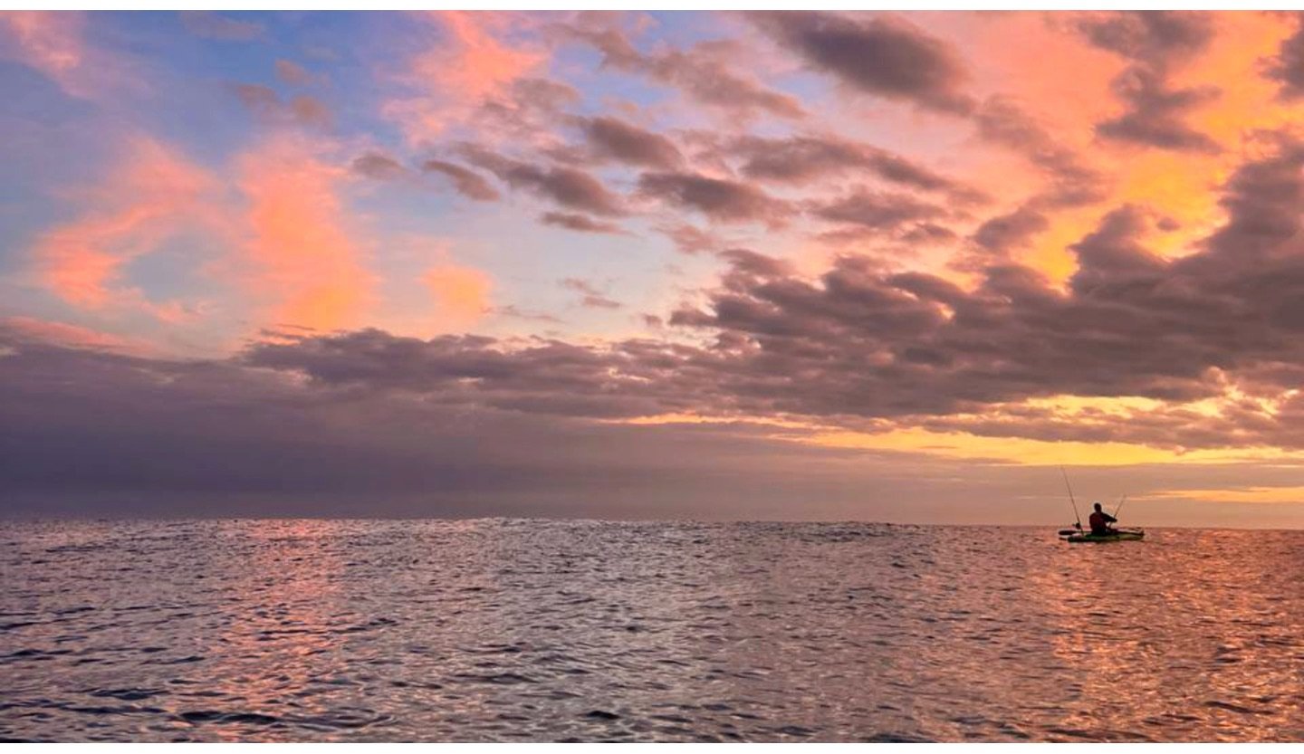 Kayak fisherman on the ocean at sunset